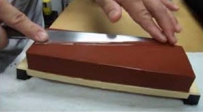 Person sharpening knife with flat whetstone